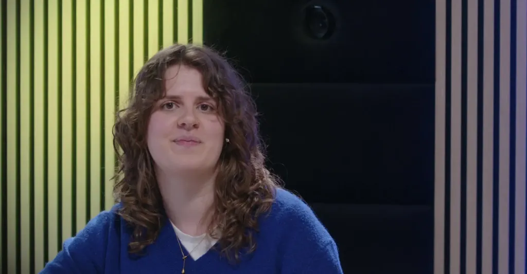 Host van de online talkshow voor de NJR in beeld, met schermen op de achtergrond
